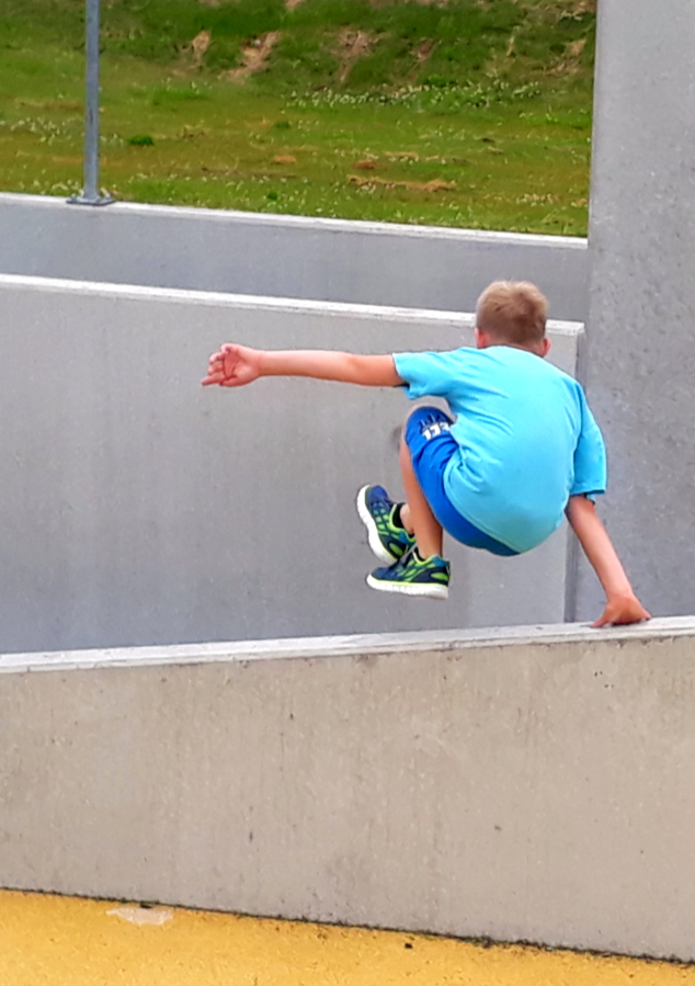 Ein Junge, der über eine Betonmauer springt.